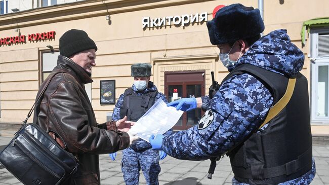 Сотрудники Росгвардии во время раздачи горожанам памяток по профилактике коронавирусной инфекции на одной из улиц в Москве