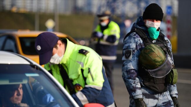 Сотрудник дорожно-патрульной службы ГИБДД проверяет документы у водителя на блокпосту при въезде в Москву со стороны Рязанского проспекта