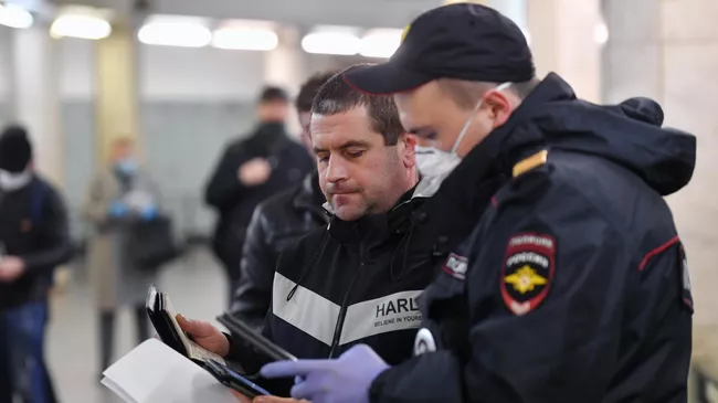 Пассажир метро показывает код своего электронного пропуска на экране смартфона сотруднику полиции на станции метро Сокольники в Москве