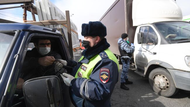 Инспектор дорожно-патрульной службы проверяет у водителя цифровой пропуск на передвижение по Москве