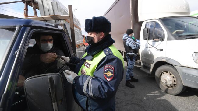 Инспектор дорожно-патрульной службы проверяет у водителя цифровой пропуск на передвижение по Москве