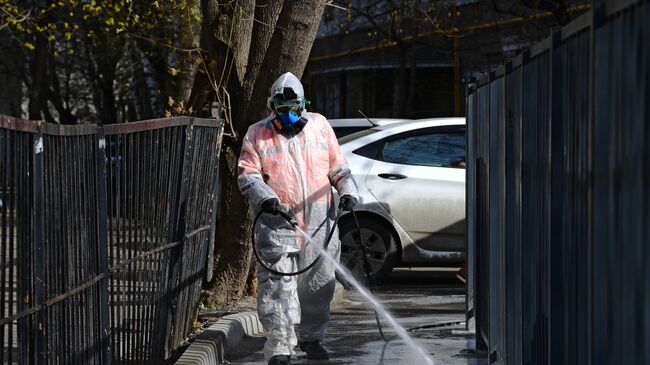 Сотрудник коммунальной службы проводит дезинфекцию внутридворовой территории в Москве