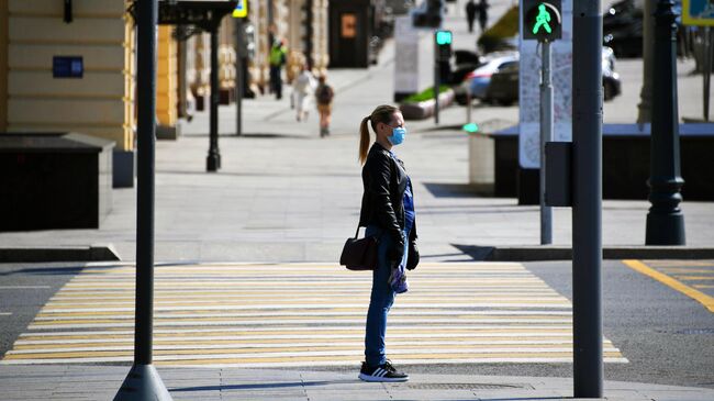 Девушка в медицинской маске и перчатках на одной из улиц в Москве