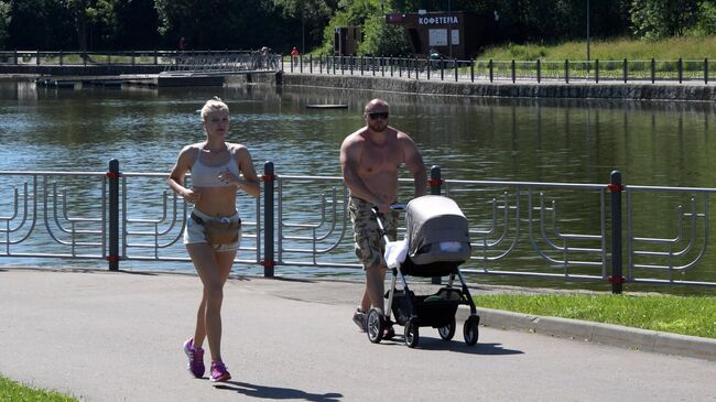 Отдыхающие в парке Олимпийской деревни во время аномальной жары в Москве