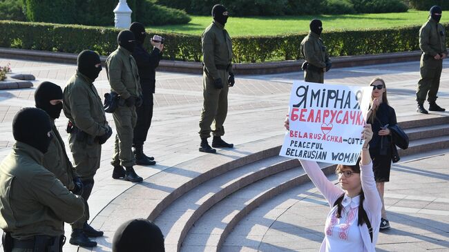 Сотрудники правоохранительных органов и участница протестной акции женщин на площади Независимости в Минске