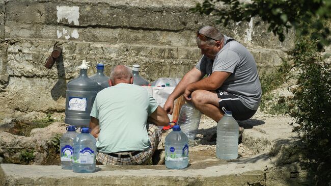 Мужчины набирают воду из родника в селе Дружное Симферопольского района