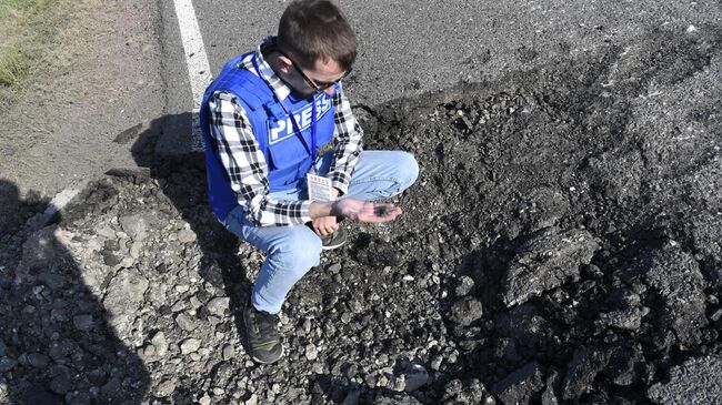 Журналист держит в руках осколок от снаряда в Мартакертском районе Нагорного Карабаха