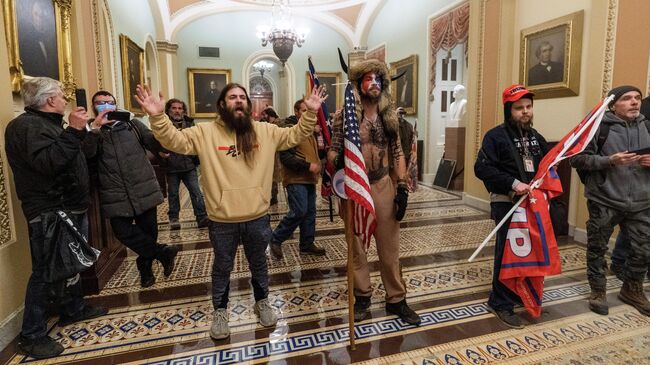 Сторонники президента Дональда Трампа выстроились напротив сотрудников полиции во время вторжения в Капитолий в Вашингтоне 