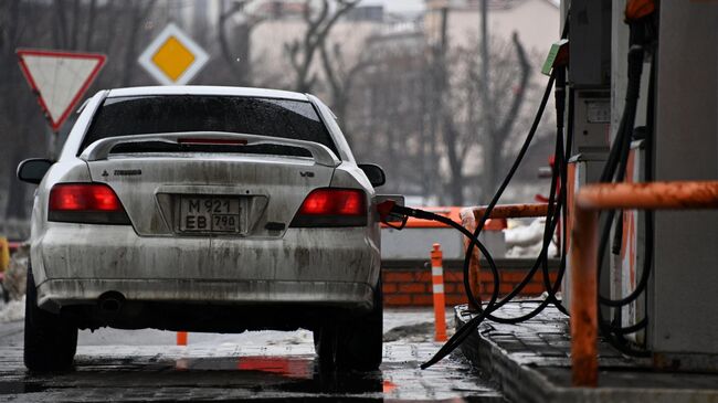 Заправщик заправляет автомобиль на одной из АЗС в Москве