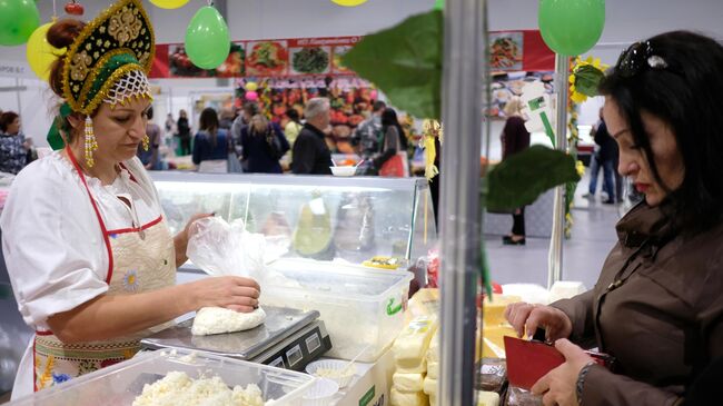 Посетительница и продавец у прилавка с молочной продукцией