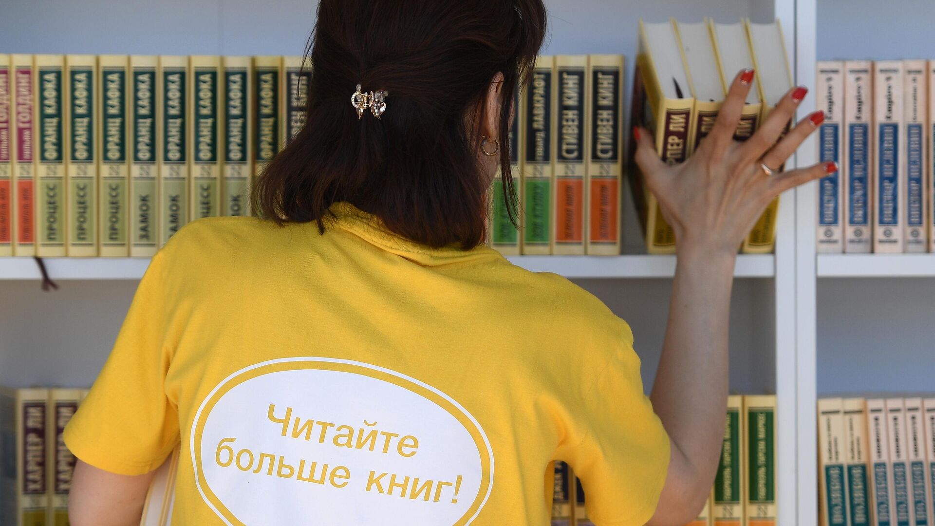 Женщина расставляет книги на полках на ежегодном российском книжном фестивале на Красной площади - РИА Новости, 1920, 25.01.2022