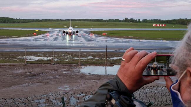 Женщина фотографирует посадку самолета авиакомпании Ryanair  в Вильнюсе 