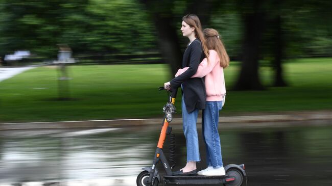 Девушки едут на электросамокате в центре Москвы