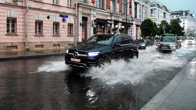 Автомобили едут по одной из улиц в Москве во время дождя