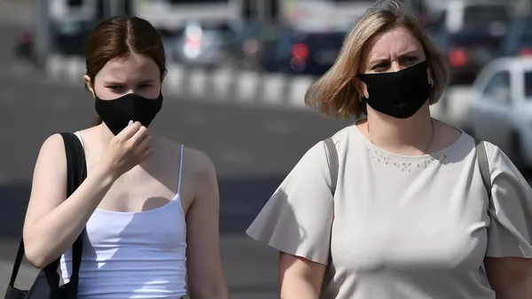 Прохожие в защитных масках на улице в центре Красноярска