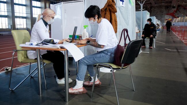 Люди в центре вакцинации от COVID-19 в легкоатлетическом манеже в Тюмени