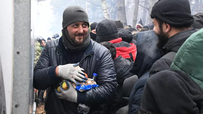 Беженцы получают гуманитарную помощь в лагере нелегальных мигрантов на белорусско-польской границе