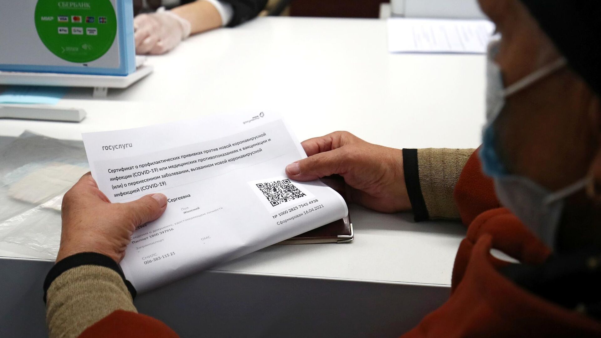 Женщина держит в руках распечатанный бумажный QR-код в многофункциональном центре госуслуг Мои документы в Волгограде - РИА Новости, 1920, 18.11.2021