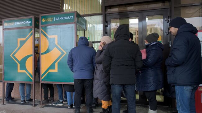 Местные жители стоят в очереди у одного из банкоматов в Нур-Султане