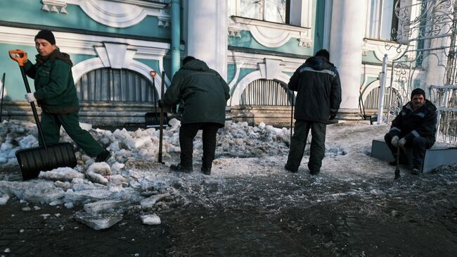 Дворники расчищают тротуар от наледи около Государственного Эрмитажа