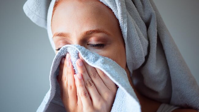 Девушка вытирает лицо полотенцем