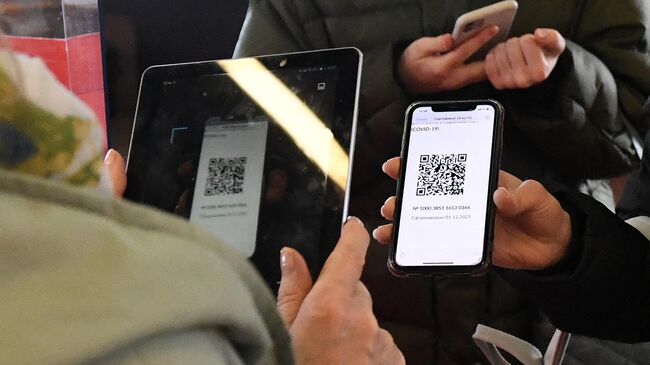 Сотрудница музея проверяет наличие QR-кода о вакцинации от CoVID-19 у посетителя музейного центра Площадь Мира в Красноярске