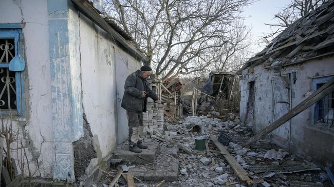 Мужчина во дворе своего дома, пострадавшего в результате обстрела в селе Тарамчук Донецкой области