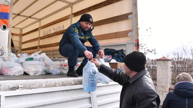 Сотрудник МЧС ДНР передает бутыли воды и продуктовый набор из гуманитарной помощи жителю села Бугас