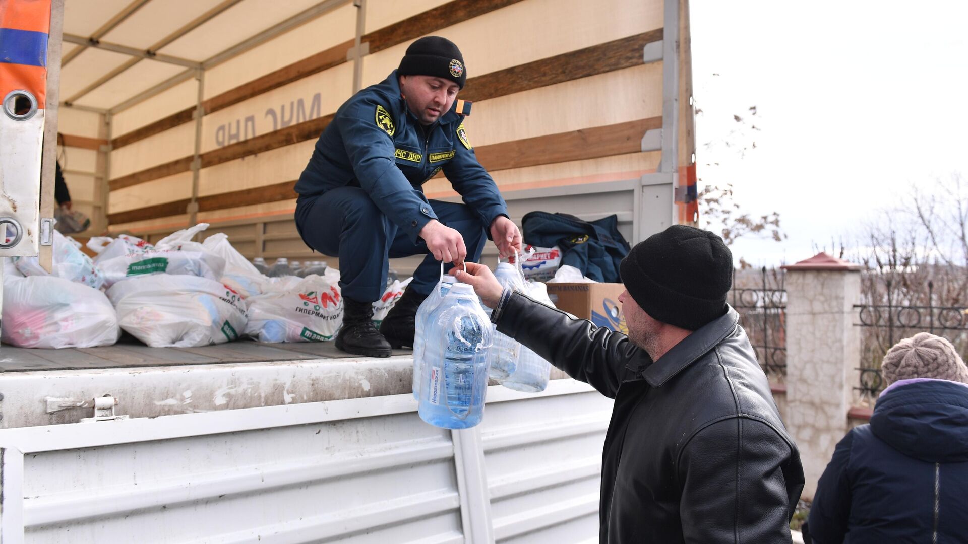 Сотрудник МЧС ДНР передает бутыли воды и продуктовый набор из гуманитарной помощи жителю села Бугас - РИА Новости, 1920, 09.03.2022