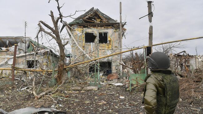 Мужчина фотографирует один из разрушенных домов села Сопино в Донецкой народной республике