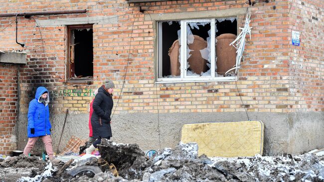 Жители Волновахи идут рядом с разрушенным домом