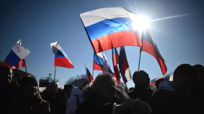 Люди смотрят трансляцию митинга-концерта, посвященного воссоединению Крыма с Россией