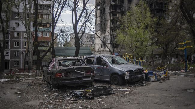 Поврежденные автомобили во дворе жилого дома в Мариуполе