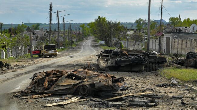 Сгоревшая военная техника и автомобили на одной из улиц в городе Рубежное