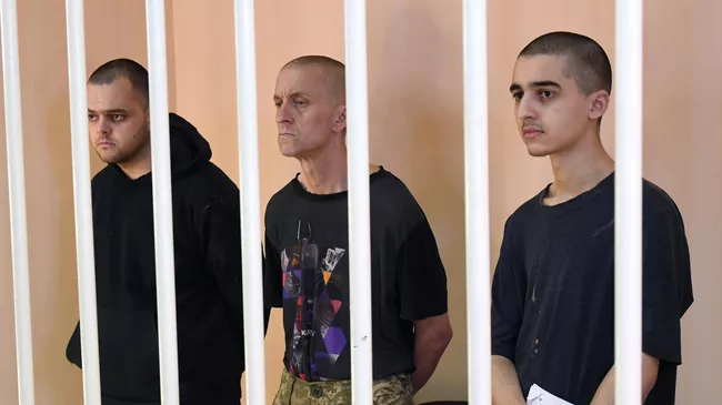 Граждане Великобритании Эйден Эслин, Шон Пиннер и подданный Королевства Марокко Саадун Брагим, обвиняемые в участии в качестве наемников в боевых действиях на территории ДНР, в зале суда в Донецке