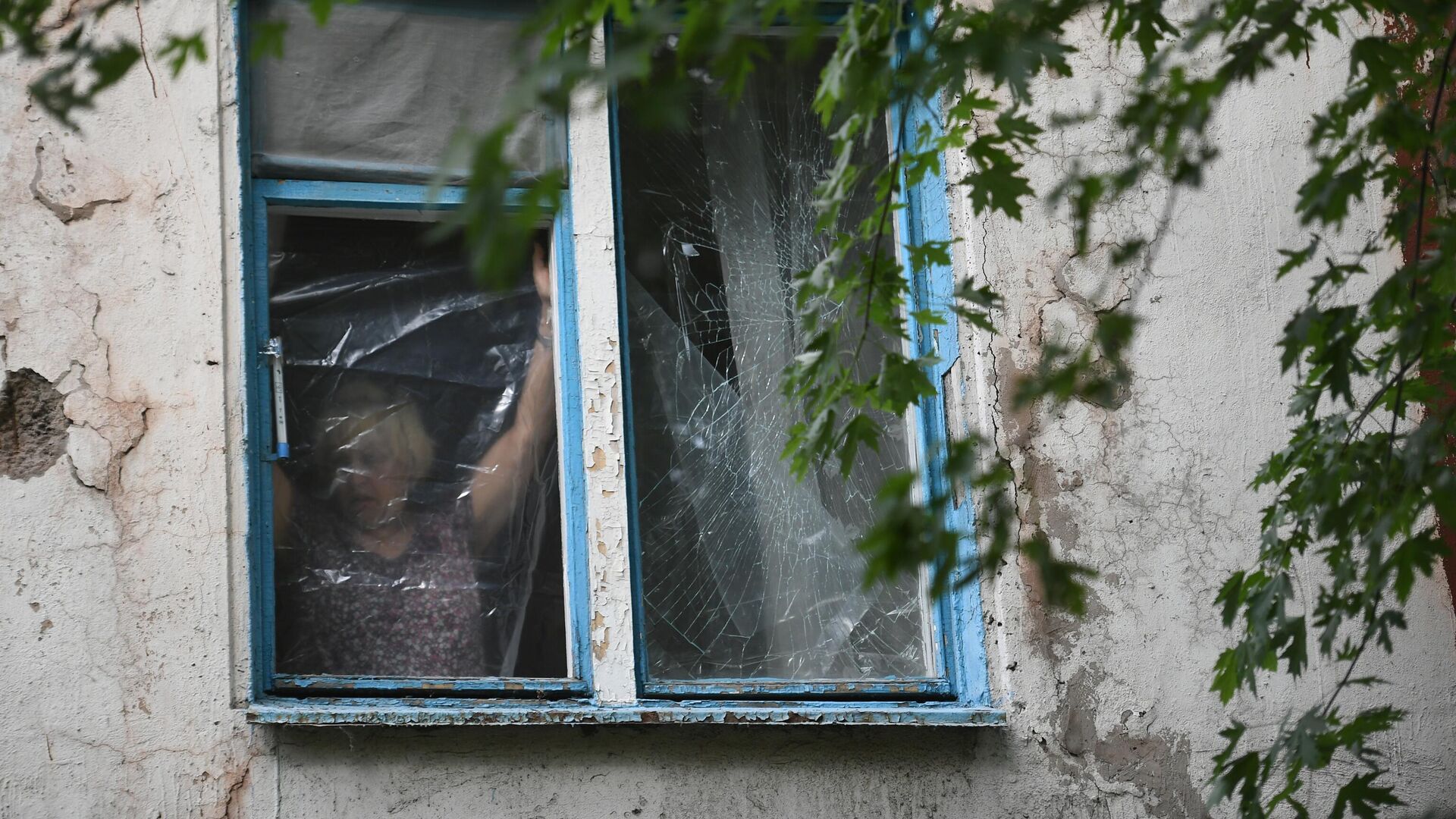 Женщина затягивает полиэтиленовой пленкой окно, разбитое в результате обстрелов  ВСУ Донецка. - РИА Новости, 1920, 06.10.2022