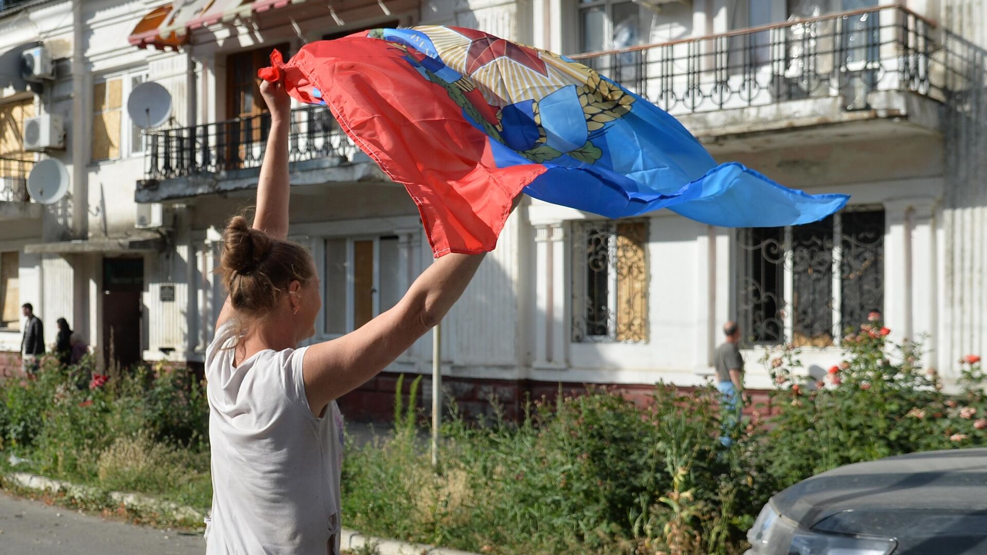 Местная жительница с флагом ЛНР, подаренным бойцами 6-го казачего полка имени Платова ЛНР и специального полка полиции имени Героя России Ахмата-Хаджи Кадырова у здания администрации в Лисичанске - РИА Новости, 1920, 04.07.2022