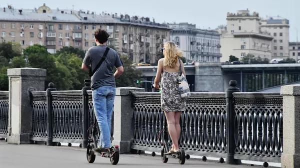 Люди катаются на электросамокатах по набережной Москвы