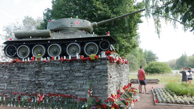 Люди фотографируются на фоне памятника танку Т-34 в городе Нарва