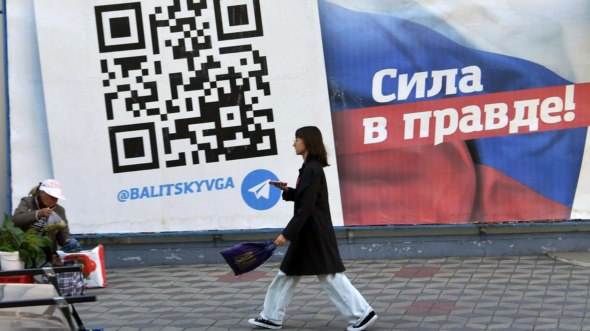 Девушка на фоне социального плаката в Мелитополе - РИА Новости, 1920, 02.10.2022