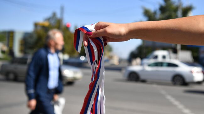 Волонтер движения Мы вместе раздает ленточки триколора в рамках подготовки к референдуму о присоединении к России 