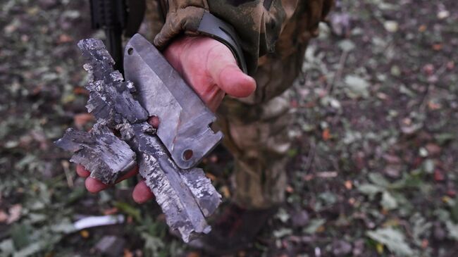 Боец демонстрирует осколки боеприпаса иностранного производства, выпущенного артиллерией ВСУ, на передовой на окраине Красного Лимана в ДНР