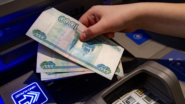 Посетитель кладет деньги на банковский счет в банкомате