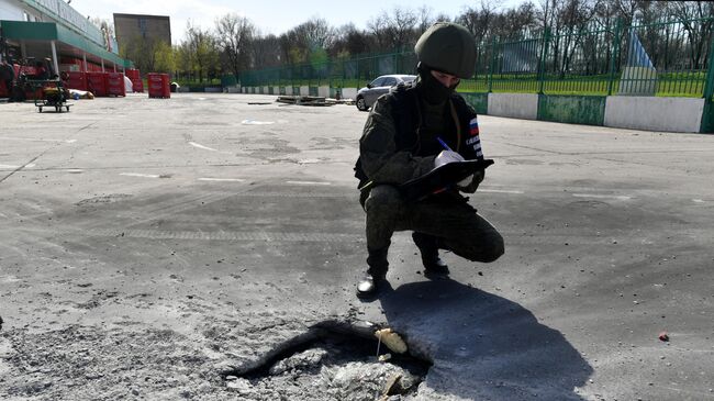 Сотрудник СКР рядом с воронкой после обстрела ВСУ торгового центра в Васильевке в Запорожской области. Архивное фото