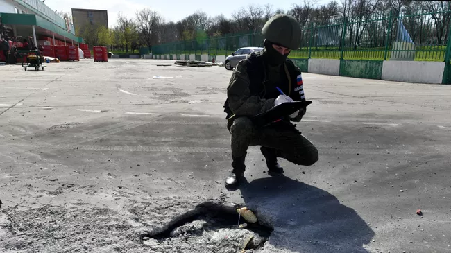 Сотрудник СКР рядом с воронкой после обстрела ВСУ торгового центра в Васильевке в Запорожской области. Архивное фото
