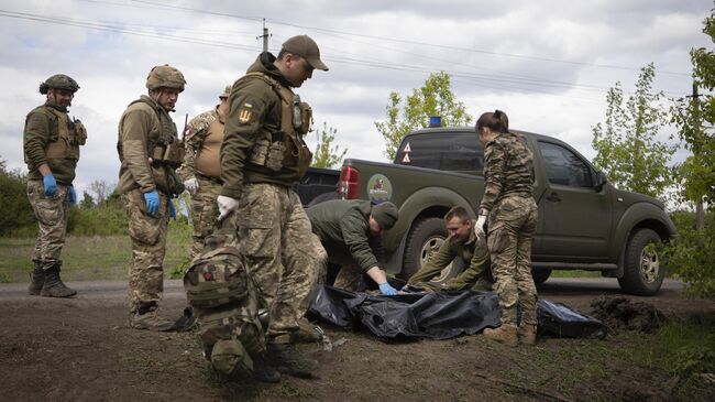 Военные медики укладывают тела убитых украинских солдат в пластиковые пакеты