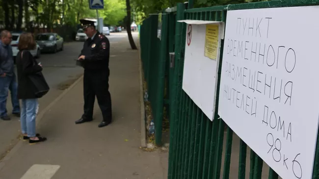 Сотрудник полиции у пункта временного размещения для жителей жилого дома, пострадавшего в результате атаки беспилотника, на улице Профсоюзная в Москве