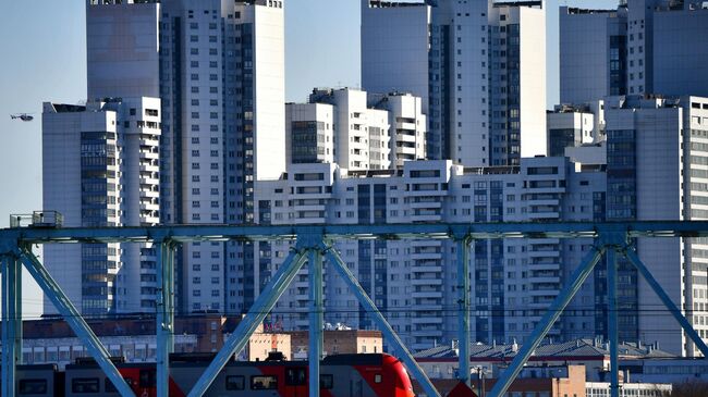 Вид на электропоезд на участке Московского центрального кольца на фоне домов в Нагатинском затоне в Москве