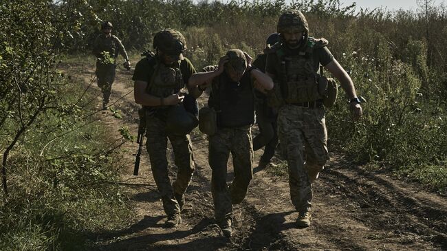 Украинские военнослужащие эвакуируют раненого солдата на передовой в Донбассе