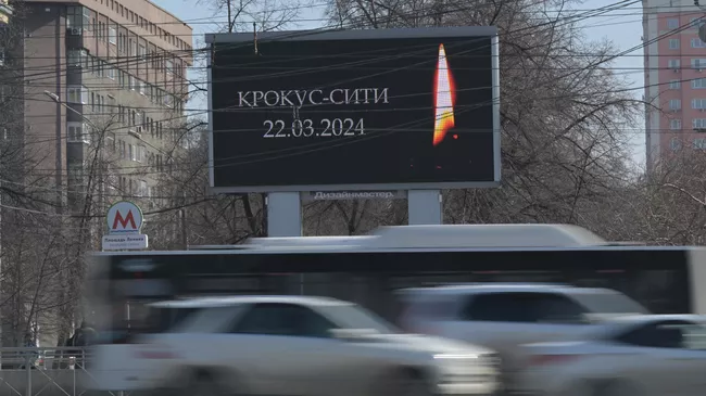 Медиаэкран с изображением свечи с траурной надписью на одной из улиц Новосибирска в память о жертвах теракта в подмосковном Крокус Сити Холле